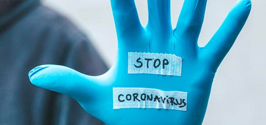 Mano con guante enseñando mensaje "Stop Coronavirus"